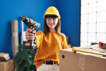 Canvas Print - Young blonde woman wearing hardhat holding drill at new home