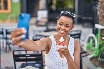 African american woman eating ice cream make selfie by smartphone at coffee shop terrace