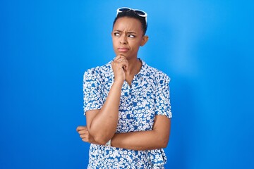 Sticker - African american woman standing over blue background thinking worried about a question, concerned and nervous with hand on chin