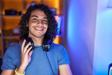 Sticker - Young latin man streamer smiling confident sitting on table at gaming room