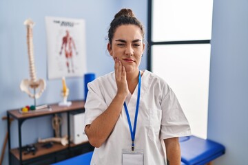 Poster - Young hispanic woman working at rehabilitation clinic touching mouth with hand with painful expression because of toothache or dental illness on teeth. dentist