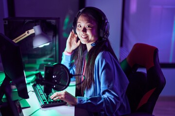 Canvas Print - Young chinese woman streamer playing video game using computer at gaming room