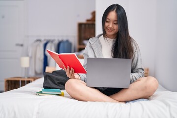 Canvas Print - Young chinese woman using laptop reading notebook studying on bed at bedroom