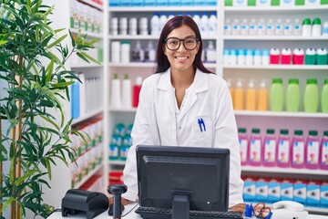 Wall Mural - Young beautiful hispanic woman pharmacist smiling confident using computer at pharmacy