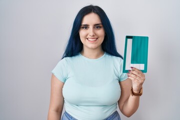 Wall Mural - Young modern girl with blue hair holding l sign for new driver looking positive and happy standing and smiling with a confident smile showing teeth