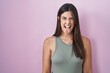Hispanic woman standing over pink background sticking tongue out happy with funny expression. emotion concept.