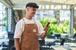 © Krakenimages.com - Young hispanic man waiter smiling confident using smartphone at coffee shop terrace