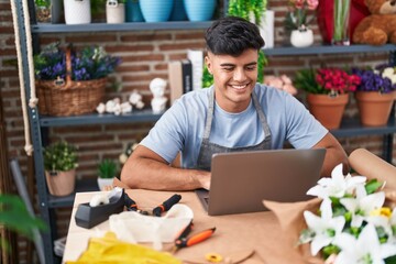 Sticker - Young hispanic man florist smiling confident using laptop at flower shop