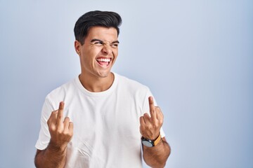 Poster - Hispanic man standing over blue background showing middle finger doing fuck you bad expression, provocation and rude attitude. screaming excited