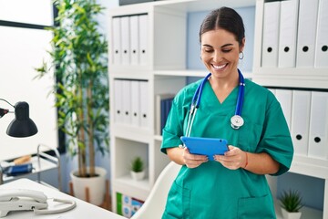 Wall Mural - Young beautiful hispanic woman doctor smiling confident using touchpad at clinic