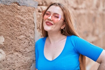 Sticker - Young redhead woman smiling confident wearing heart sunglasses over isolated brick background