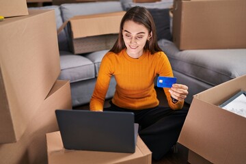 Sticker - Young caucasian woman using laptop and credit card sitting on floor at new home