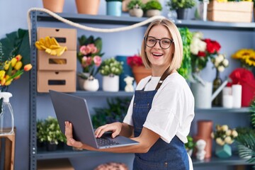 Poster - Young blonde woman florist smiling confident using laptop at florist shop