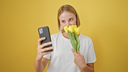 Sticker - Young blonde woman holding bouquet of flowers making selfie by smartphone over isolated yellow background