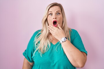 Canvas Print - Caucasian plus size woman standing over pink background looking fascinated with disbelief, surprise and amazed expression with hands on chin