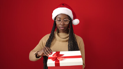 African woman unpacking gift over isolated red background