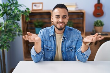 Canvas Print - Young hispanic man sitting on table speaking at home