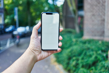 Man holding smartphone showing white blank screen at amsterdam