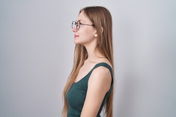 Canvas Print - Young caucasian woman standing over white background looking to side, relax profile pose with natural face and confident smile.