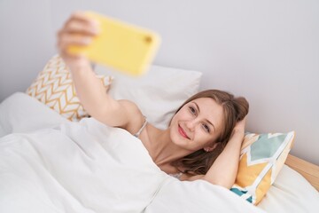 Wall Mural - Young caucasian woman make selfie by smartphone lying on bed at bedroom