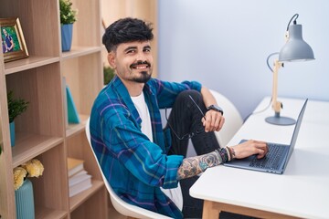 Poster - Young hispanic man using laptop sitting on table at home