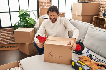 Wall Mural - Middle age man smiling confident packing cardboard box at new home