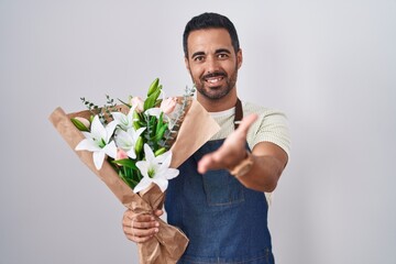 Sticker - Hispanic man with beard working as florist smiling cheerful offering palm hand giving assistance and acceptance.