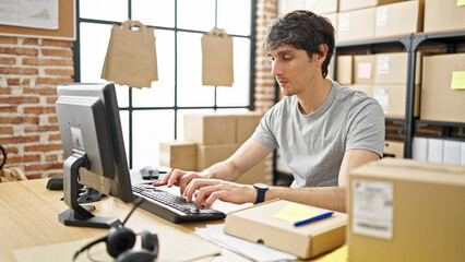 Wall Mural - Young hispanic man ecommerce business worker typing on computer with serious face at office