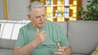 © Krakenimages.com - Middle age grey-haired man sitting on sofa speaking at home