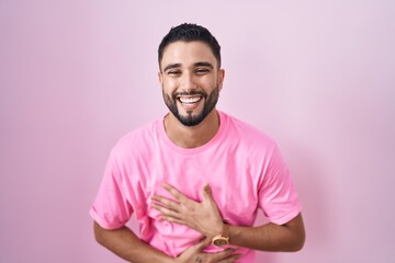 Sticker - Hispanic young man standing over pink background smiling and laughing hard out loud because funny crazy joke with hands on body.