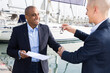 Two men in suits buy and sell a yacht in the seaport