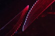 Cuchillo dentado de metal con dientes muy afilados, se utiliza para cortar y rebanar sin hacer fuerza, con luz roja-azulada forma un diseño original abstracto con fondo negro