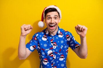 Sticker - Photo of funky young student guy prepare new year holiday fists up hooray astonished santa claus gifts isolated on yellow color background