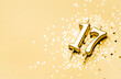 17 years celebration festive background made with golden candle in the form of number Seventeen lying on sparkles. Universal holiday banner with copy space.