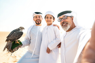 Wall Mural - Three generation family making a safari in the desert of Dubai. Grandfather, son and grandson spending time together in the nature and training their falcon bird.