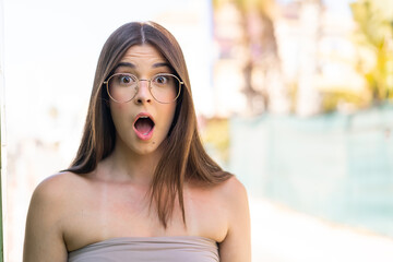 Wall Mural - Young pretty Brazilian woman at outdoors With glasses and surprised expression