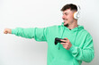 Young handsome man playing with a video game controller isolated on white background giving a thumbs up gesture