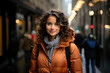 Portrait of a smiling young woman in an orange jacket on a bustling city street, exuding trendy urban fashion and confidence.