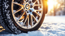 Close up of car tire stands in the snow in winter, the sun shines from behind the wheel