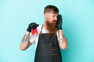 Wall Mural - Butcher man wearing an apron and serving fresh cut meat isolated on blue background with headache