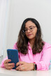 © Thales - Portrait of a psychopedagogue, wearing pink clothes, in her office, sitting, looking at the appointments scheduled on her cell phone. Helps with school performance.