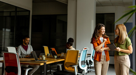 Wall Mural - Two young business women with digital tablet in the office