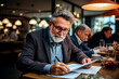 © Antonio - Senior businessman working with papers in cafe. Senior man working with papers in cafe