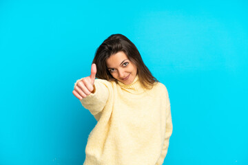 Young caucasian woman isolated on blue background with thumbs up because something good has happened