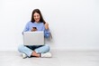 © luismolinero - Young caucasian woman with laptop sitting on the floor isolated on white background surprised and sending a message
