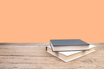 Wall Mural - Composition with hardback books, fanned pages on wooden deck table and orange background. Books stacking. Back to school. Copy Space. Education background.