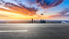 Asphalt Road And City Skyline With Colorful Sky Clouds At Sunset