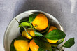 Overhead view of a bowl of fresh ripe tangerines against a grey background