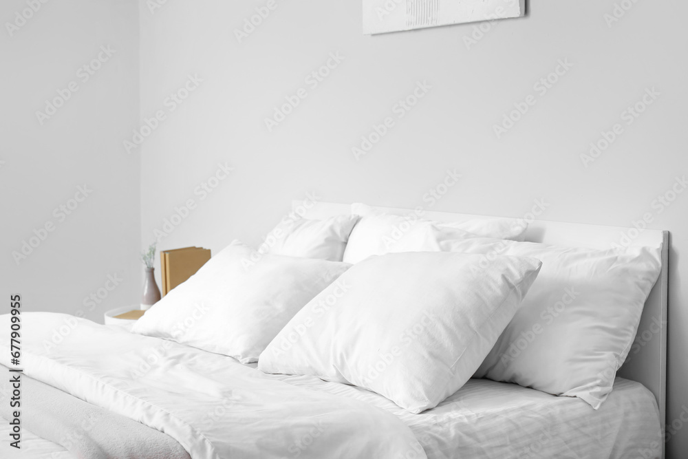 Large double bed with white pillows in interior of light bedroom