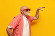 © Богдан Маліцький - pensioner old grandfather in sunglasses dances and sings to music at party on yellow isolated background
